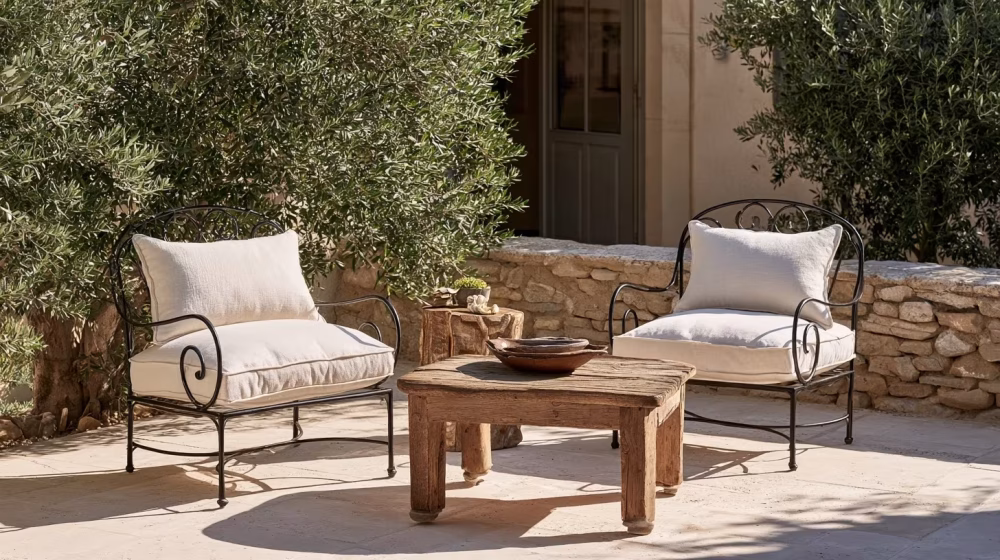 Fauteuils en fer forgé et table en bois brut sur une terrasse provençale