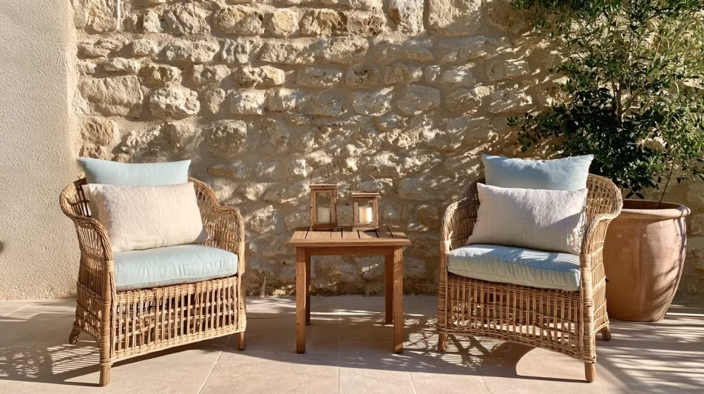 Coussins pastel, linge naturel et lanternes sur un salon de terrasse provençal